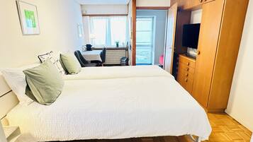 Un dormitorio con una cama, un armario de madera y un escritorio con una silla.