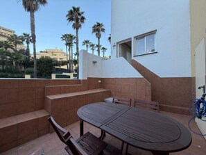 Een terras met een tafel en stoelen, een trap en een gebouw op de achtergrond.