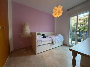 Ein Schlafzimmer mit Bett, Nachttisch, Stehlampe und Blick nach draußen.