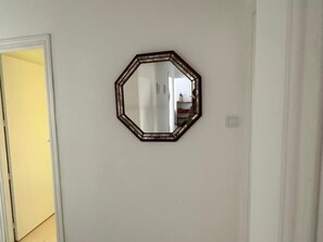 Ein Zimmer mit einer schlichten weißen Wand, einer Tür und einem gerahmten Spiegel.