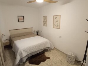 A bedroom with a bed, a nightstand, a wall-mounted shelf, and a small rug. - 3-Bedroom Apartment on San Miguel Street, in the Heart of Torremolinos (Torremolinos)