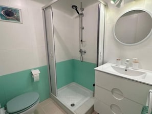 Een badkamer met douche, toilet en wastafel.