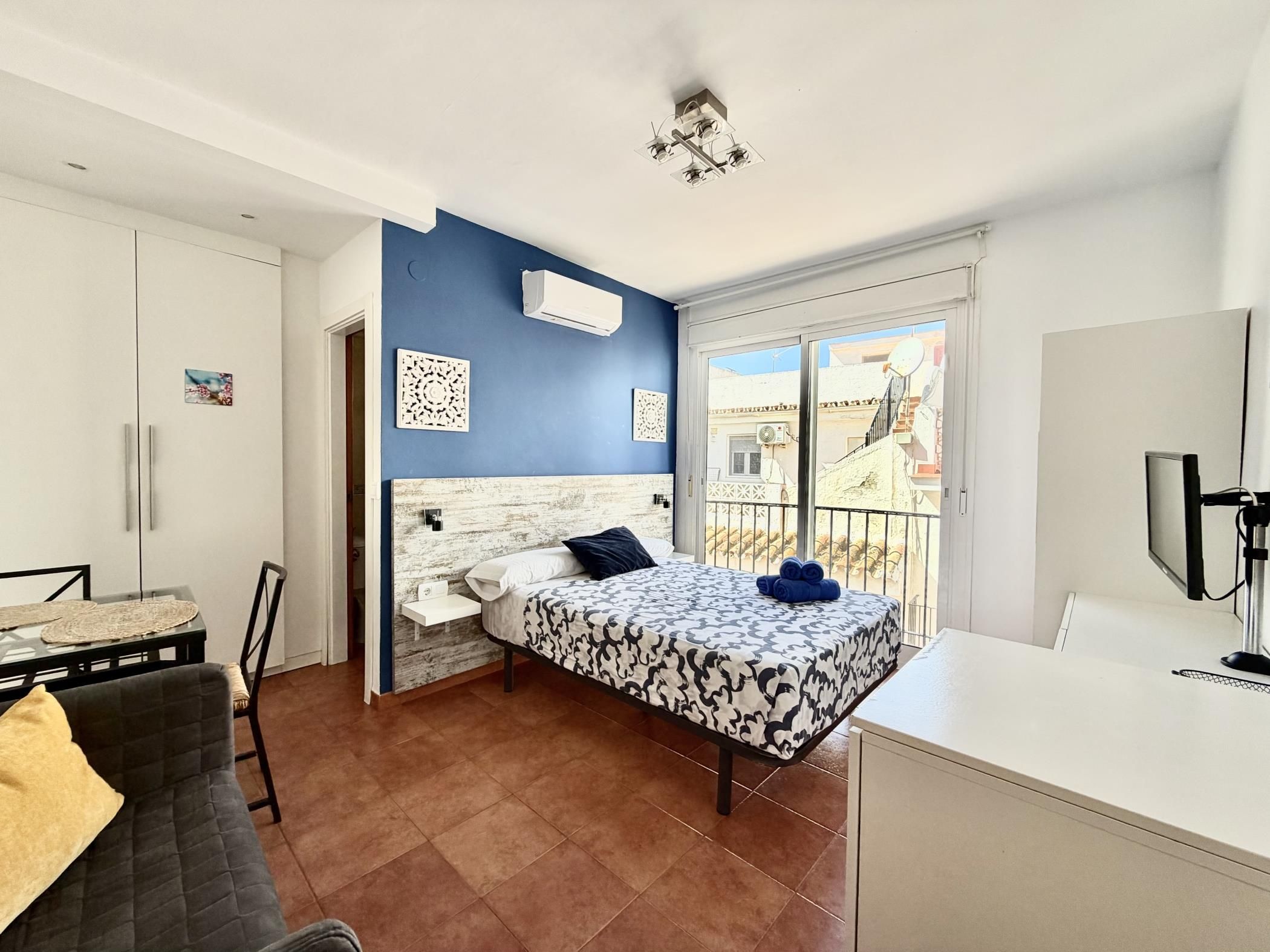 Une chambre à coucher avec un lit, un bureau, une chaise et un balcon offrant une vue.