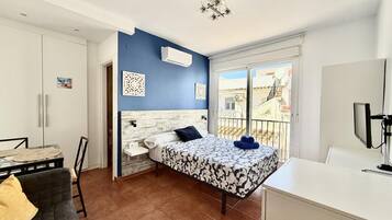 Une chambre à coucher avec un lit, un bureau, une chaise et un balcon offrant une vue.