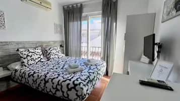 Hotellihuone, jossa on sänky, työpöytä, tuoli, televisio ja ikkuna, jossa on verhot.