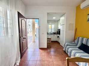 Een kamer met een bed, een slaapbank, een kitchenette en een deur naar buiten.
