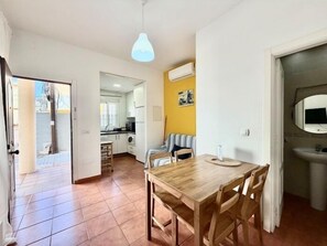 Een ruimtelijk ingerichte leefruimte met een eethoek, kitchenette en een badkamer met spiegel.