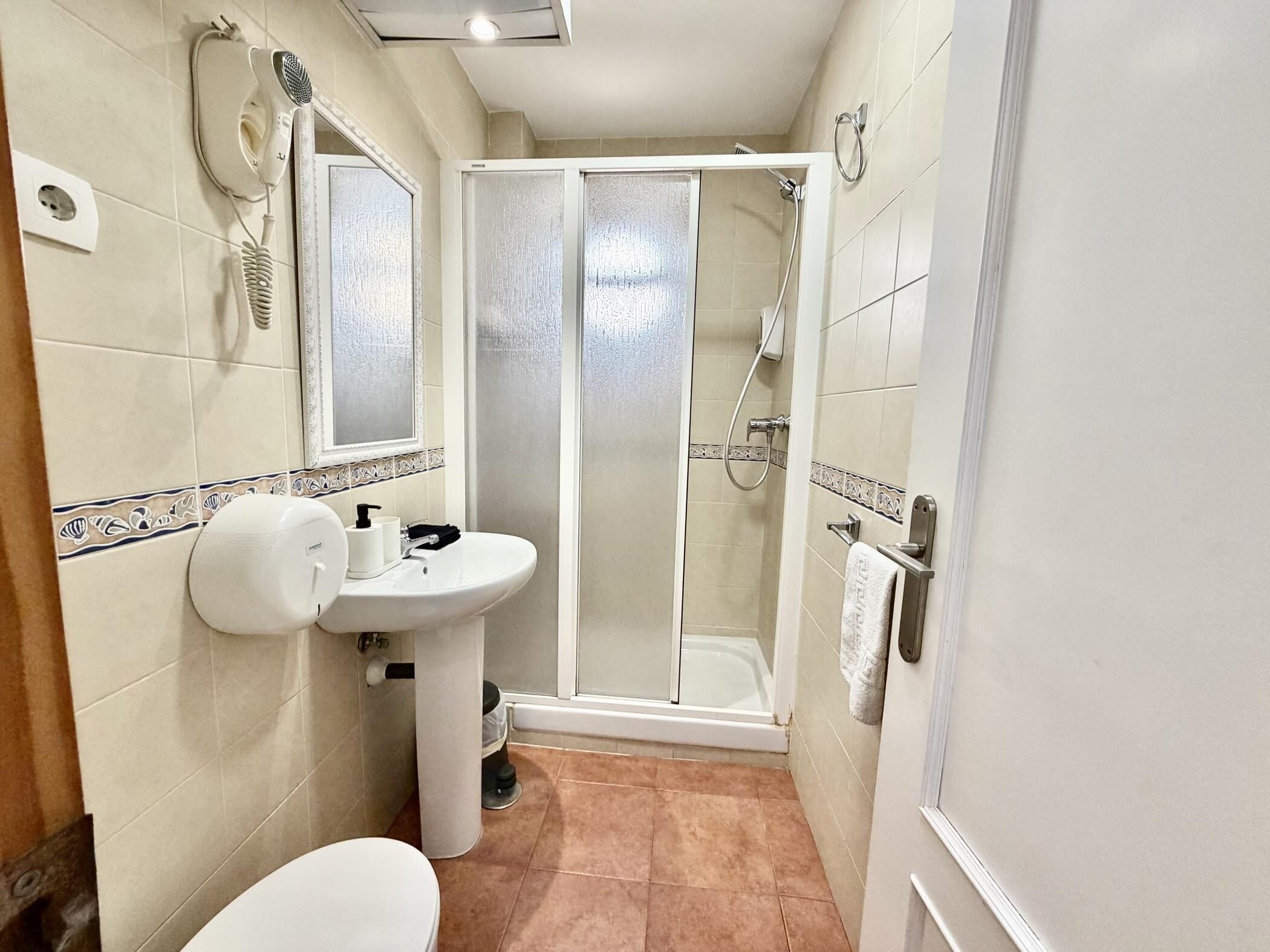 A bathroom with a toilet, sink, and shower.
