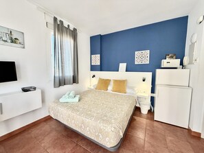 A hotel room with a bed, a desk, a television, and a refrigerator. - Sea-View Studio by La Carihuela Beach, Torremolinos (Torremolinos)