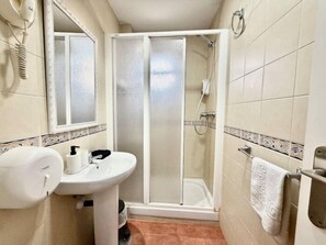 Een badkamer met een douche, een wastafel en een spiegel.