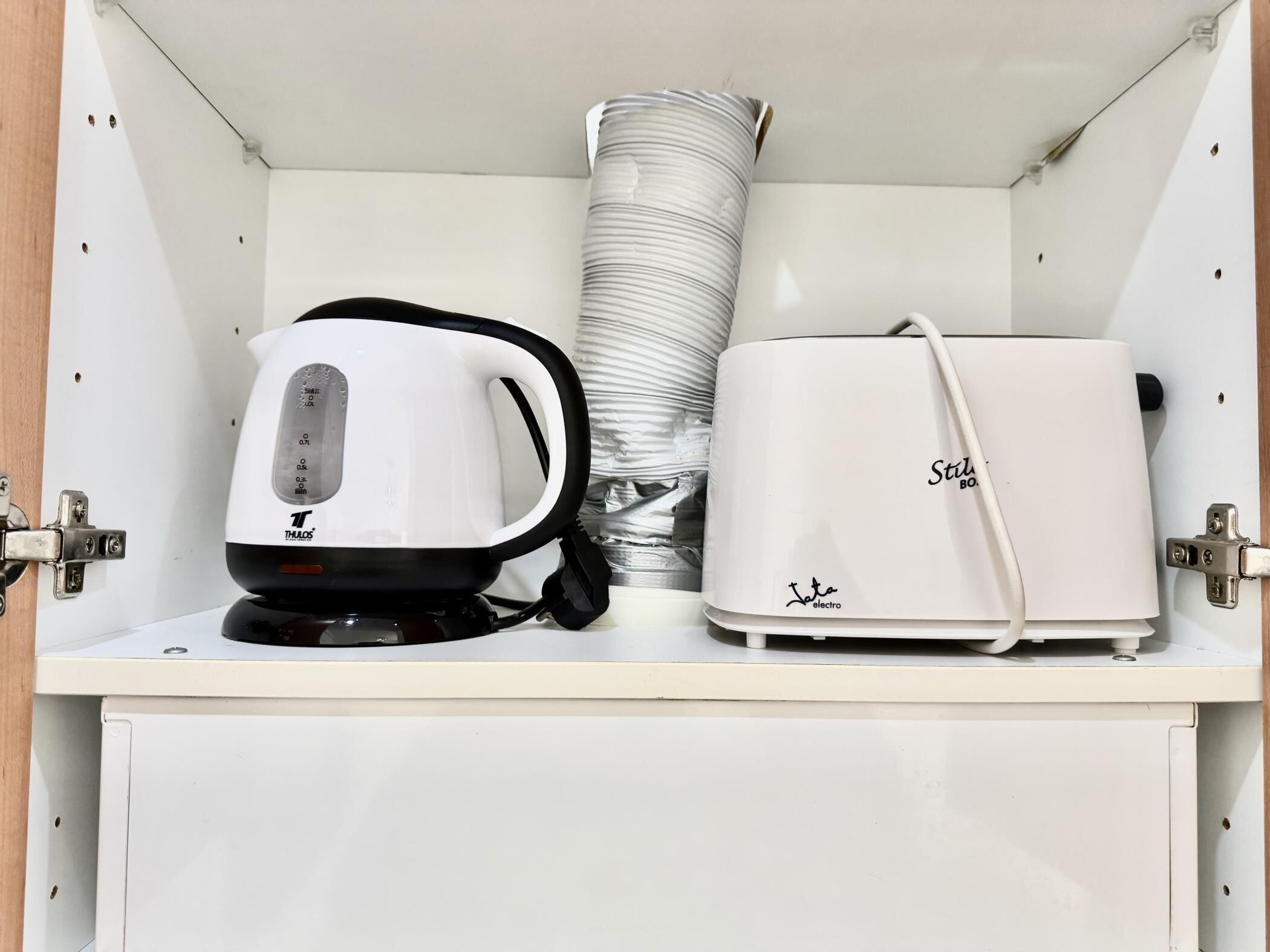 Un mueble blanco con una tetera y un tostador encima.