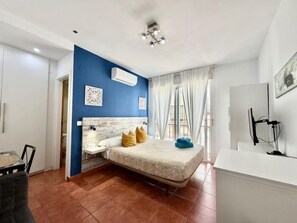 Een slaapkamer met een bed, een bureau en een stoel.