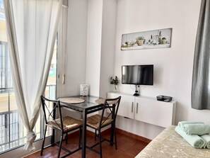 Ein modernes Zimmer mit Esstisch, Stühlen, einem Flachbildfernseher und einem kleinen Schrank.