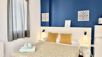 A hotel room with a bed, two nightstands, a white cabinet, a window with curtains, and decorative wall panels.