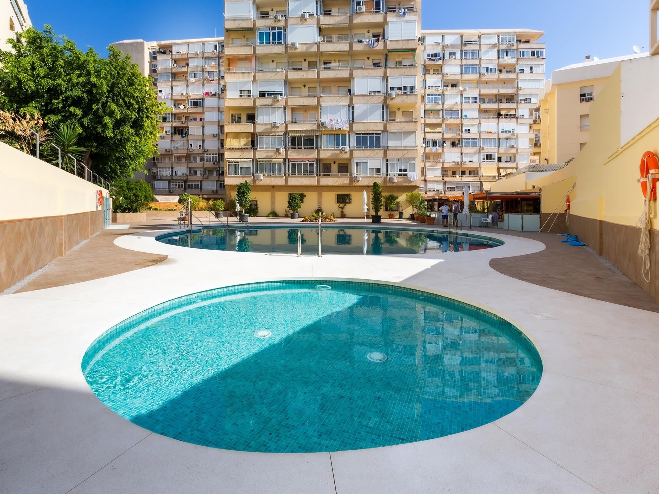Edificio residencial con piscina y zona de estar al aire libre.
