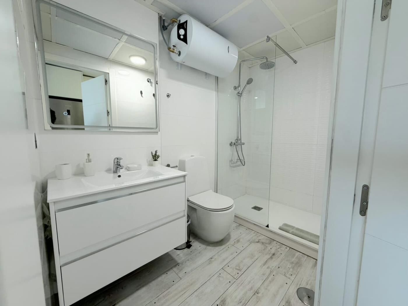 Un bagno moderno con un mobile lavabo bianco, un WC e una cabina doccia in vetro.