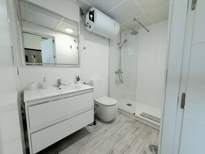 Een moderne badkamer met een witte wastafel, een toilet en een douchecabine met glazen wanden.