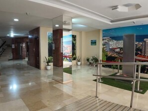 Eine Hotelhalle mit Empfangsschalter, einer Treppe und einem Stadtbild-Mural.