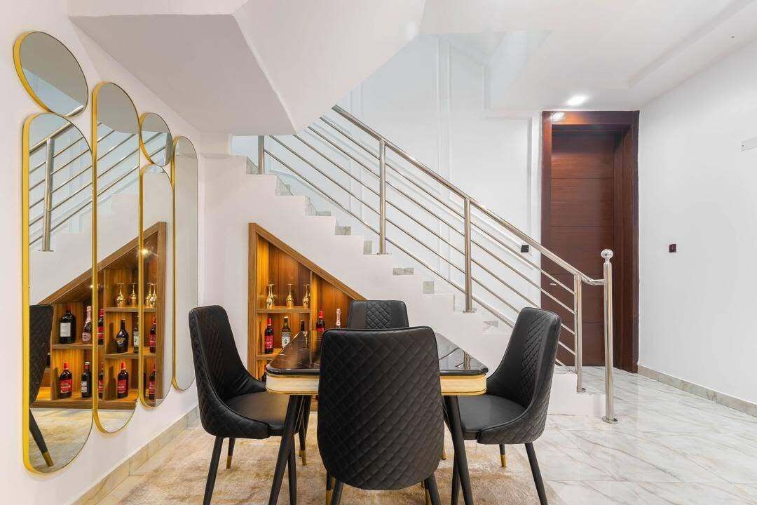 A dining area with a table and chairs, a wine rack, and a staircase.