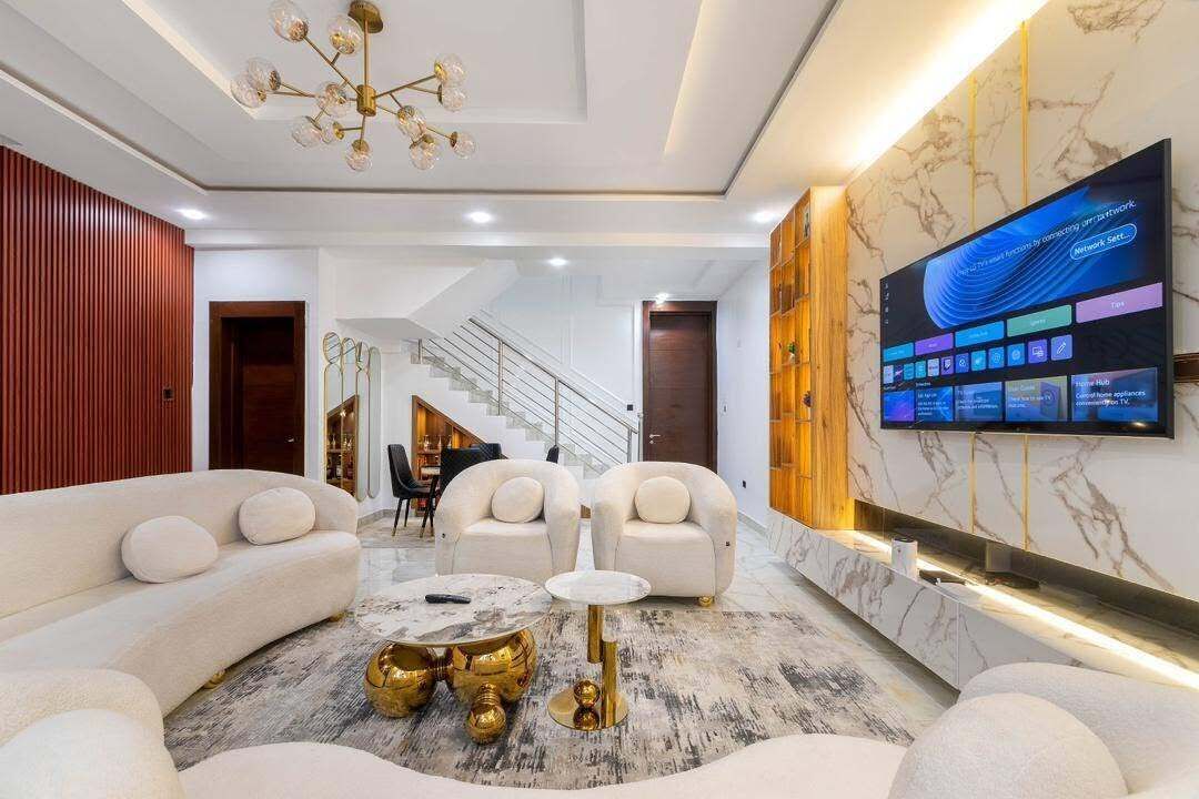 A modern living room with a sofa set, a coffee table, and a TV mounted on the wall.