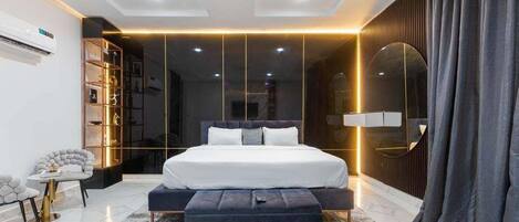 A modern bedroom with a large bed, bedside tables, a wardrobe, and a mirror.
