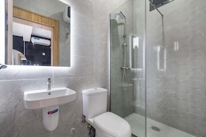 A modern bathroom with a white sink, toilet, and glass-enclosed shower. - Velora Apartment (Owerri)