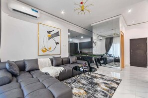 A modern living room with a sectional sofa, a coffee table, and a large mirror.
