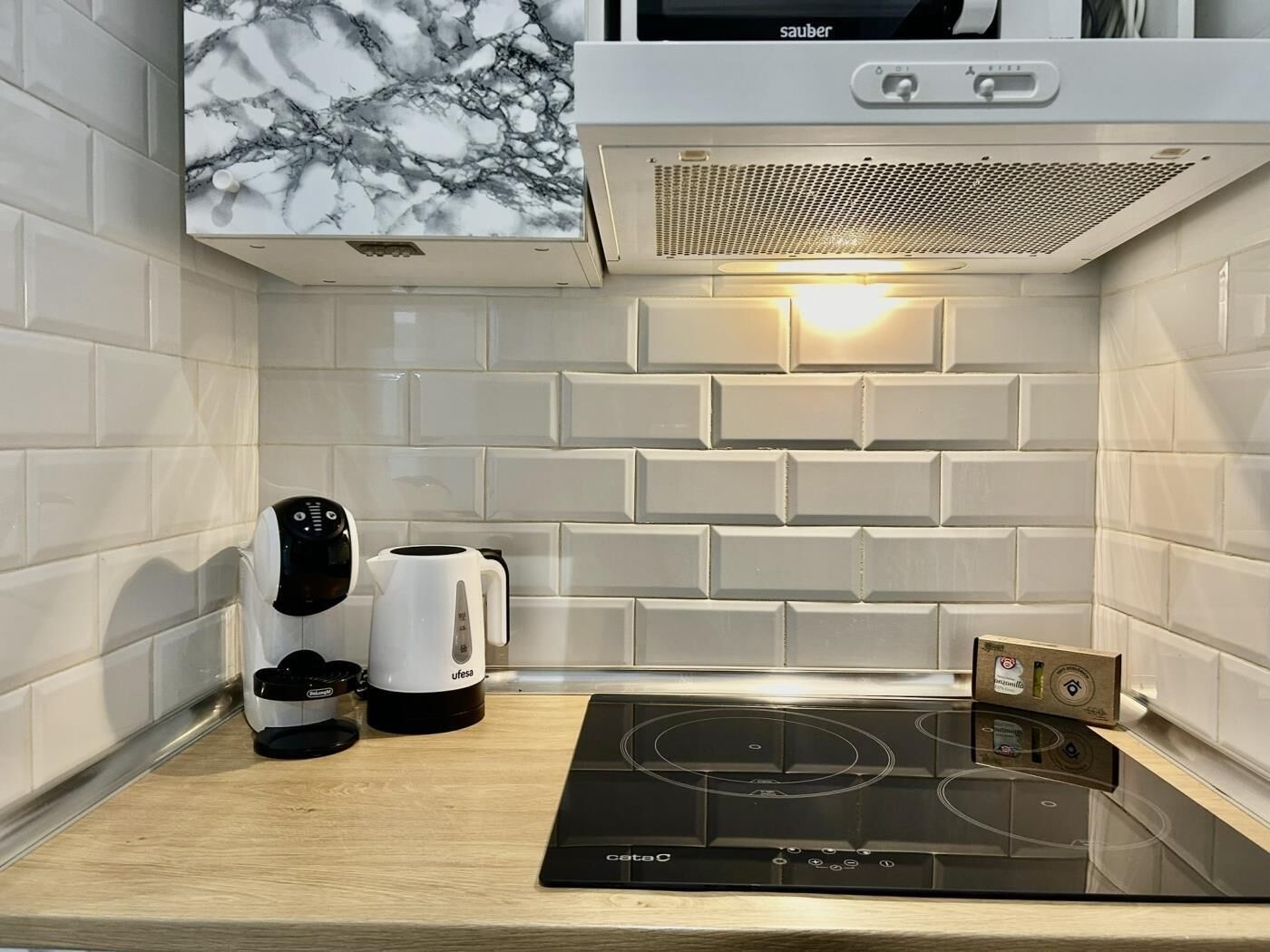A kitchen with a built-in microwave, a coffee maker, and an induction cooktop.