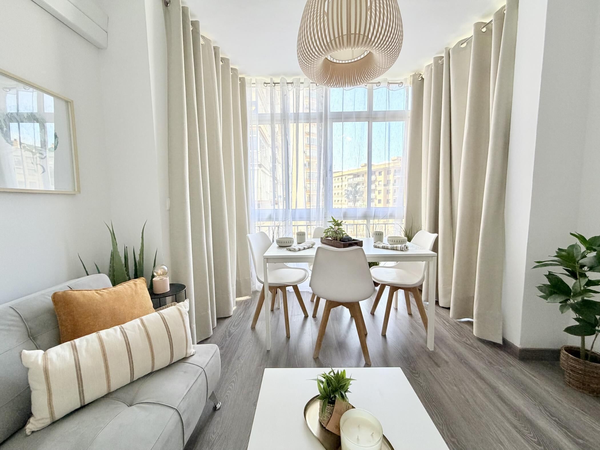 A modern living room with a sofa, dining table, chairs, and a coffee table.