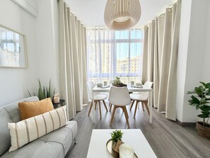 A modern living room with a sofa, dining table, chairs, and a coffee table. - Newly Renovated Apartment with A/C and WiFi in Central Torremolinos (Torremolinos)