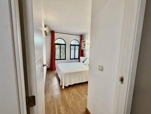 A bedroom with two beds, a window with a view, and a door leading to another room. - Ground-Floor Apartment with Private Terrace 125 m from the Beach, La Colina (Torremolinos)
