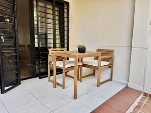 Een houten tafel met stoelen op een betegelde vloer, met een bloempot op de tafel.