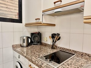 Una cocina con estufa integrada, cafetera y hervidor sobre la encimera.