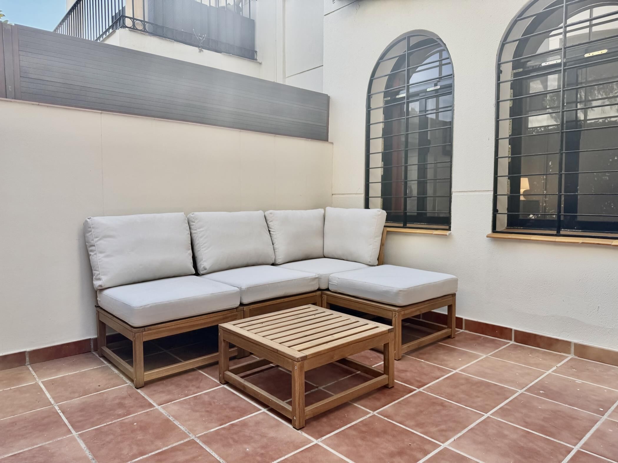 Un coin salon avec un canapé et une table en bois, un sol carrelé et un mur avec une fenêtre.