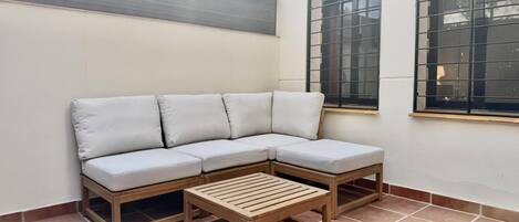 Un coin salon avec un canapé et une table en bois, un sol carrelé et un mur avec une fenêtre.