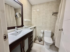 Een badkamer met een wastafel, spiegel, toilet en douchegordijn.