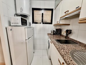 A compact kitchen with white appliances, a window, and a granite countertop. - Ground-Floor Apartment with Private Terrace 125 m from the Beach, La Colina (Torremolinos)