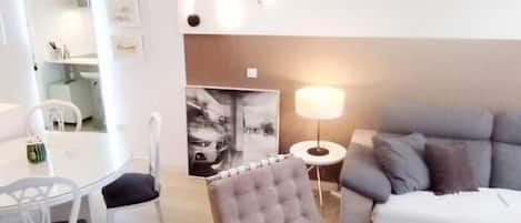 A modern living room with a grey sofa, a tufted armchair, a round coffee table, and a side table with a lamp.
