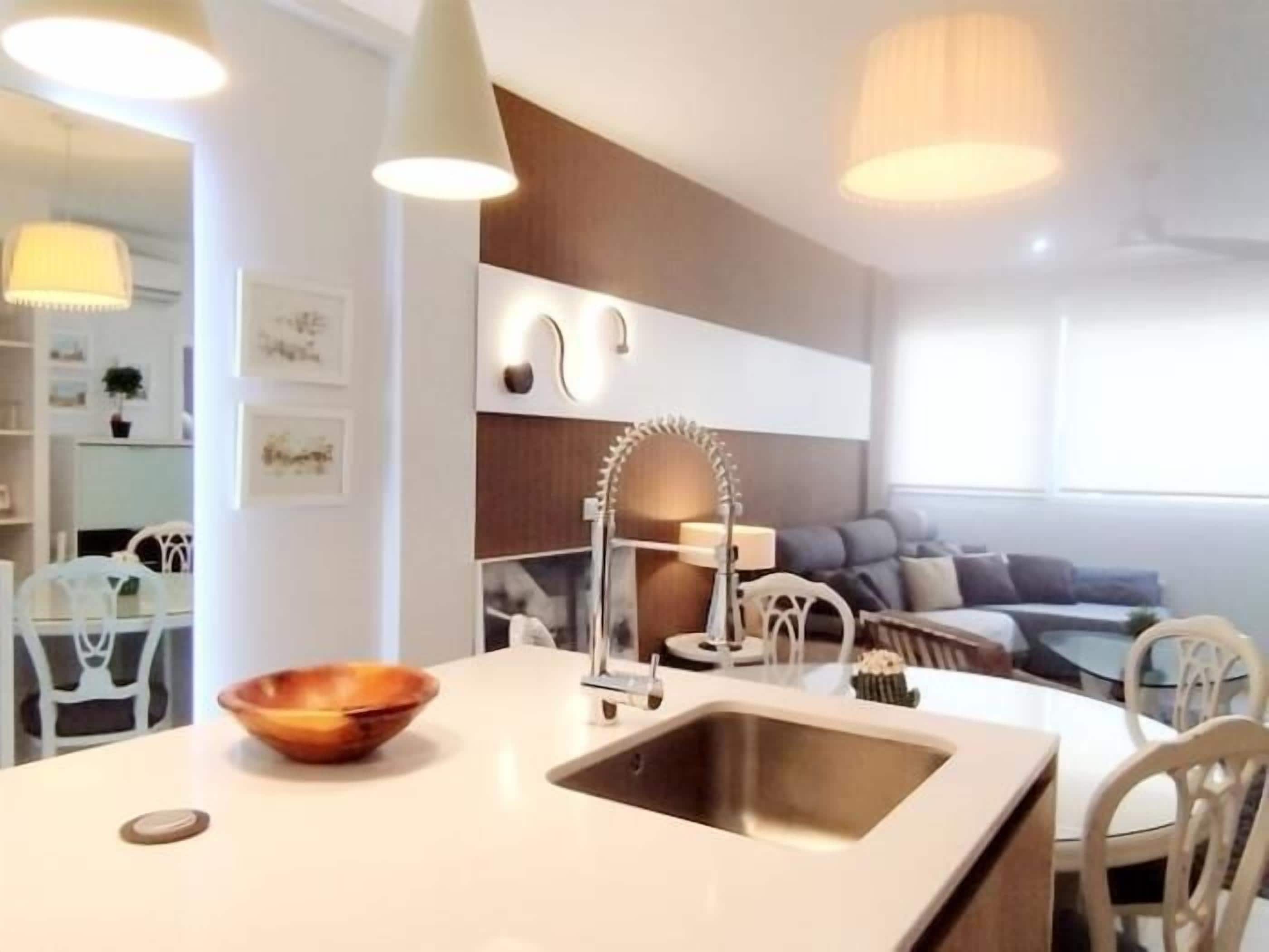 Een moderne keuken met een centraal eiland, een inbouwspoelbak en hanglampen.