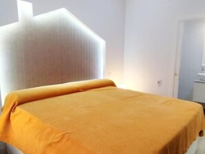 Een kamer met een bed, een raam en een deur.