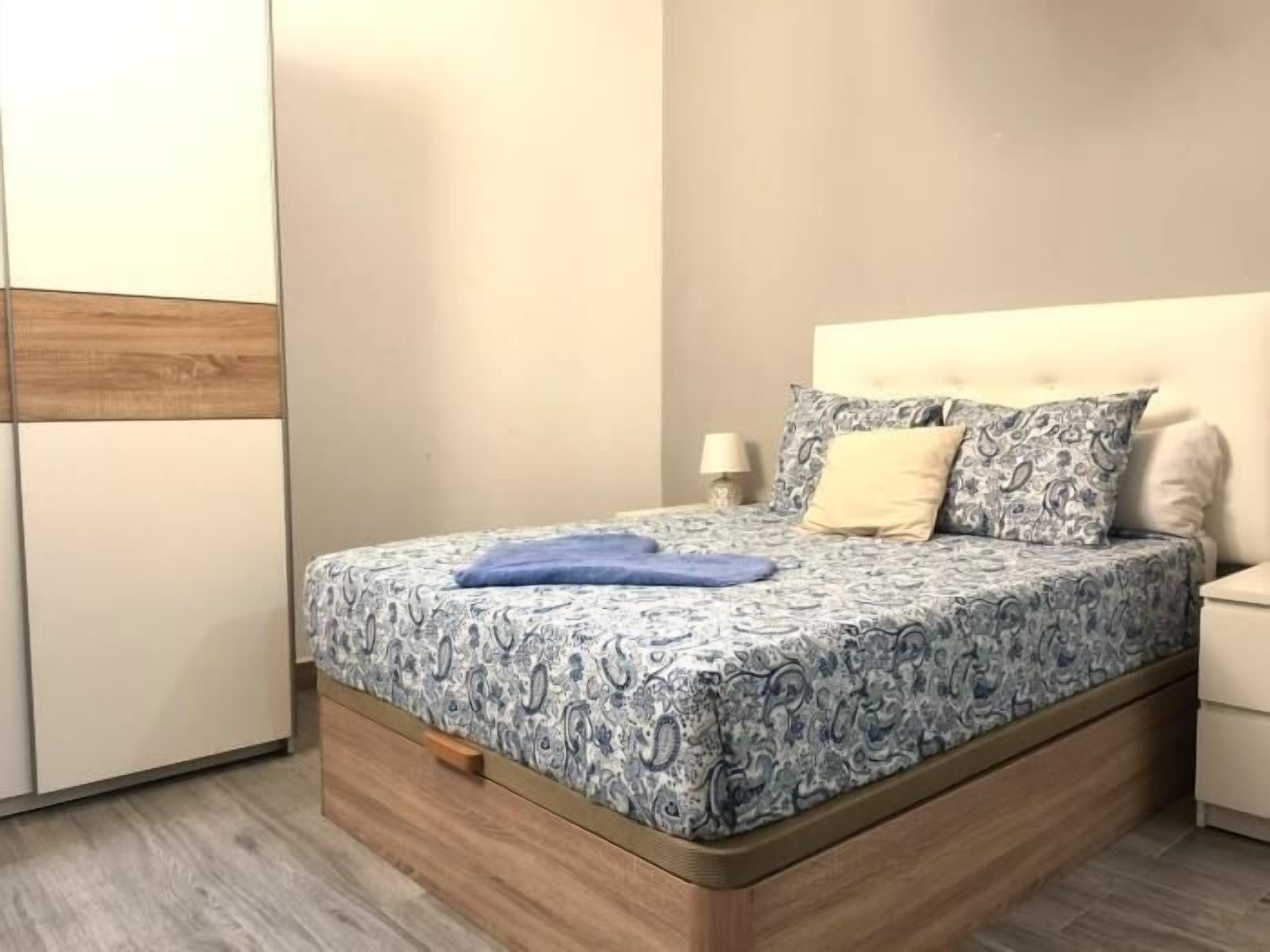Quarto com cama, mesa de cabeceira, luminária e guarda-roupa.
