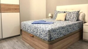 Quarto com cama, mesa de cabeceira, luminária e guarda-roupa.