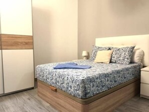 A bedroom with a bed, bedside table, lamp, and a wardrobe. - Brand-New Studio 130 m from Bajondillo Beach, Torremolinos (Torremolinos)
