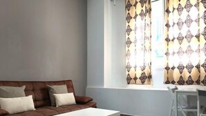 Sala de estar com sofá marrom, mesa de centro branca e janela com cortinas estampadas.