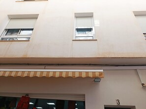 A building facade with three windows, a storefront with awning, and a visible door number '3'. - Brand-New Studio 130 m from Bajondillo Beach, Torremolinos (Torremolinos)