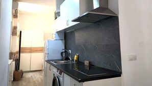Uma cozinha compacta com fogão embutido, pia e micro-ondas.