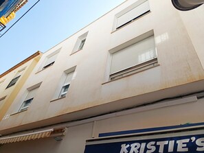 Un edificio con numerose finestre, alcune dotate di persiane, e un negozio con insegne.