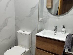 Een badkamer met toilet, wastafel en spiegel.