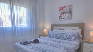 Uma cama bem arrumada com colcha estampada, cabeceira e duas luminárias de mesa.