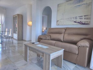 Ein modernes Wohnzimmer mit einer Couch, einem Couchtisch und einem Essbereich mit Stühlen.